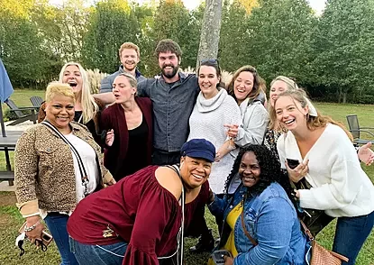 A joyful group of friends smiling and posing together outdoors during a Vino Virginia wine country tour, capturing the spirit of community and shared adventure.